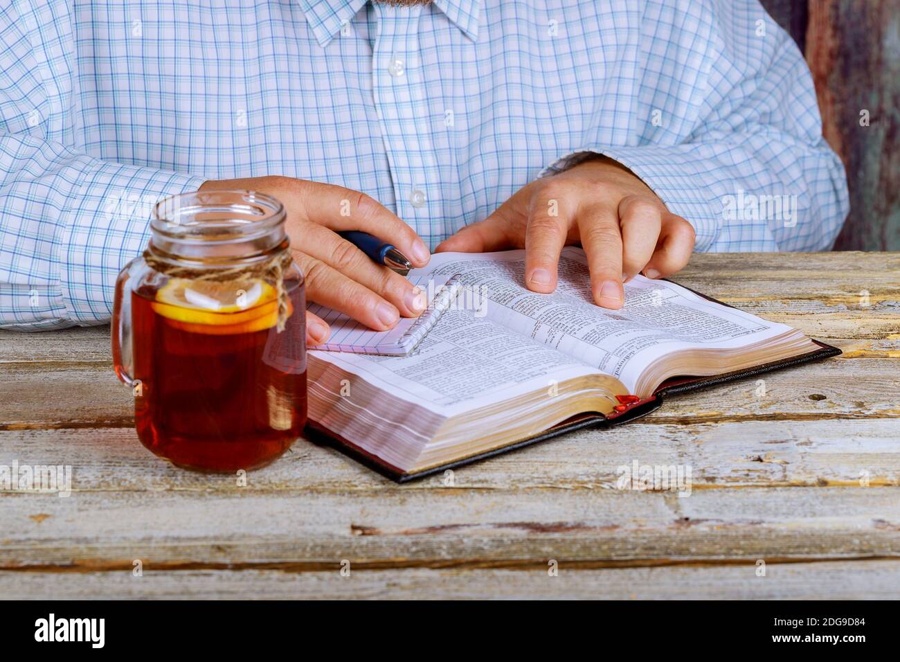 Man reading the Bible as well as tea on the table Stock Photo