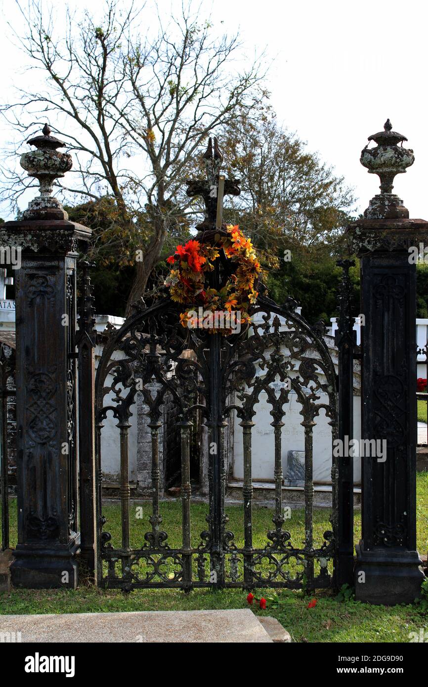 a dark antique ornate iron gate is decorated with an autumn wreath Stock Photo