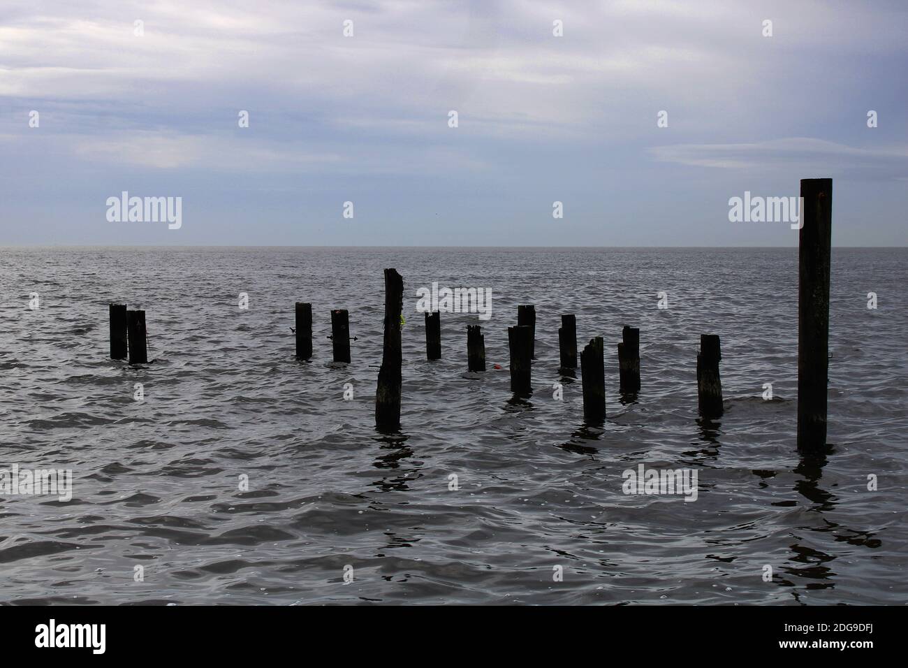 silhouette of old wooden pier posts across the water Stock Photo