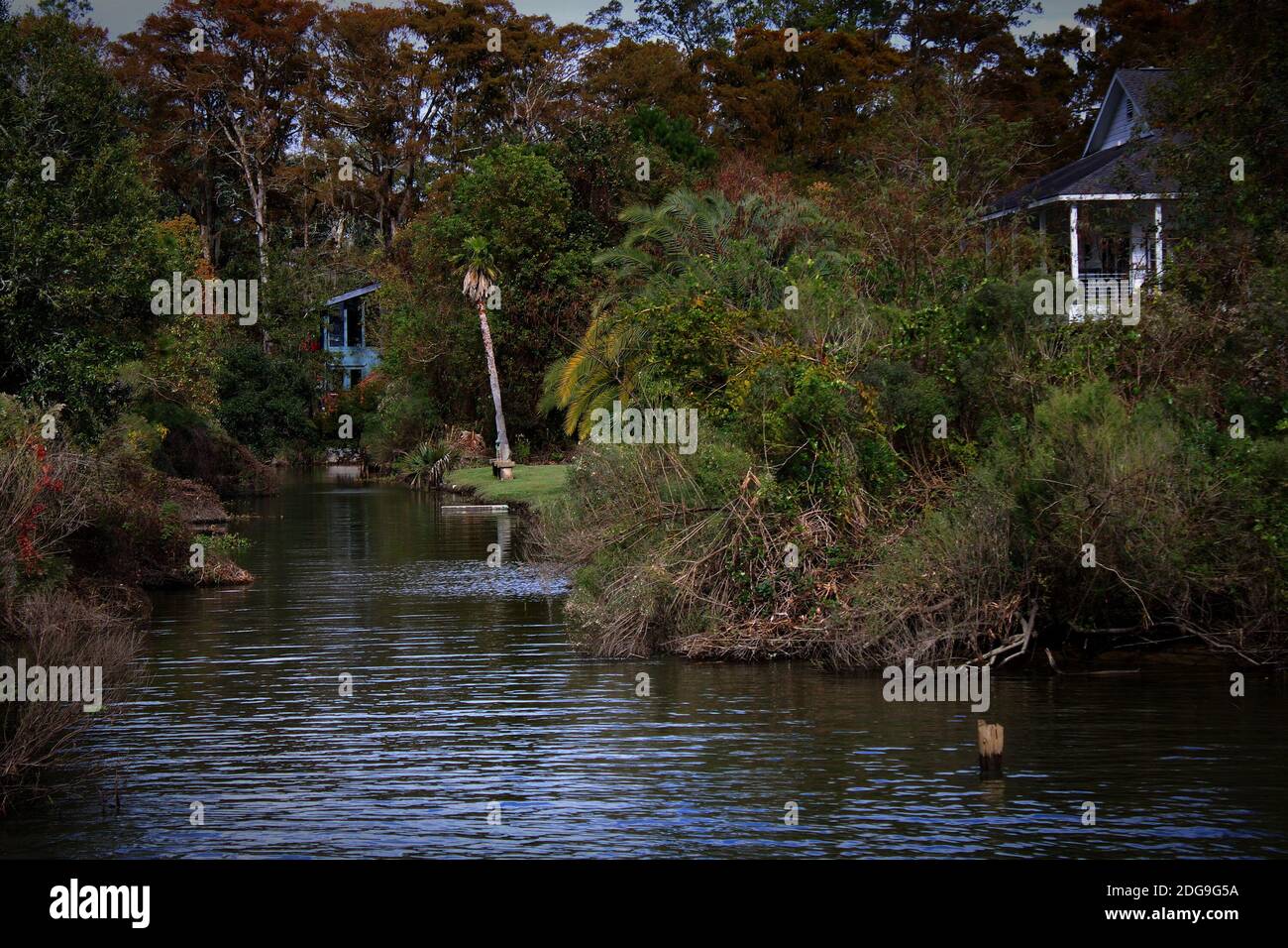 lush greenery conceals cottages along the banks of this quiet canal Stock Photo