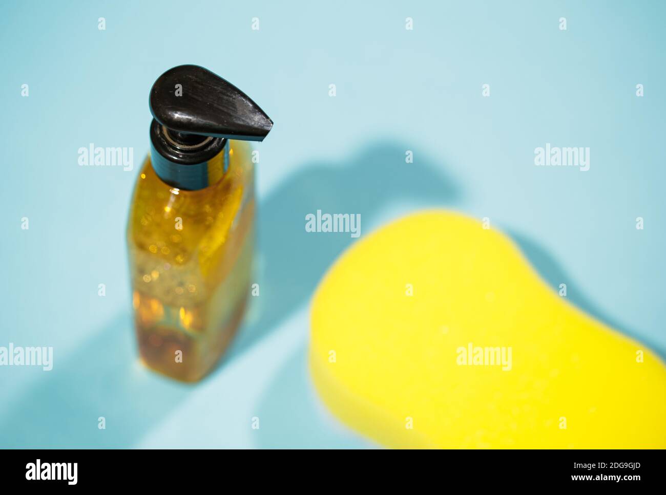 Top view of yellow sponge with bath gel on blue background, Hygiene