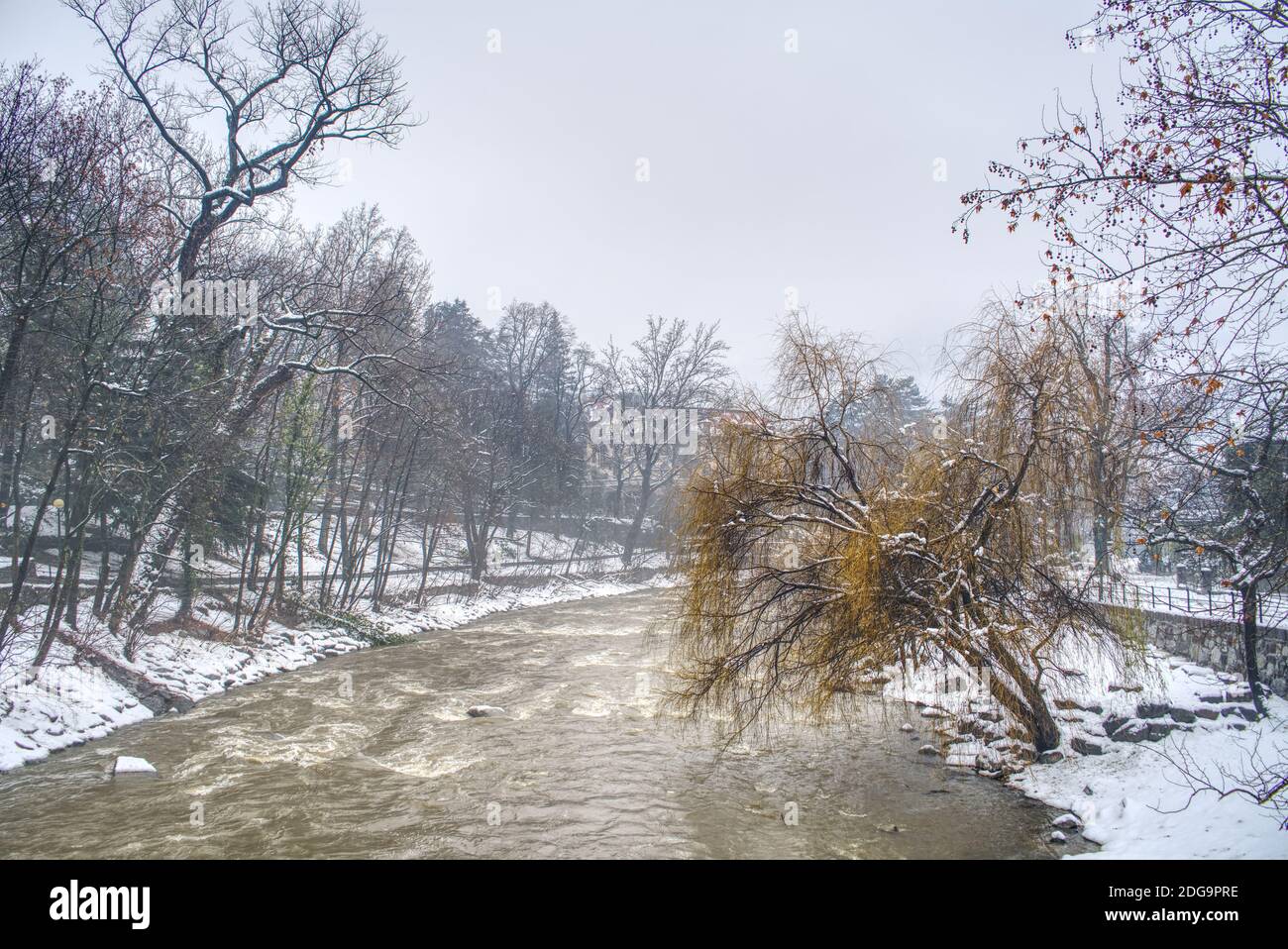 Passer river's dirty water after a heavy snowfall and its promenade on the sides in Merano, Italy covered by wet snow. Stock Photo