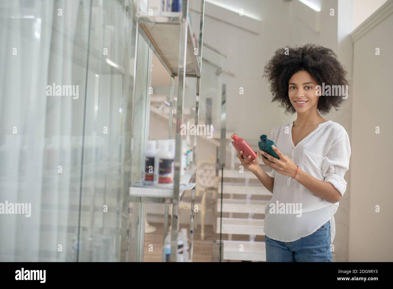 Young woman in beauty center choosing cosmetics Stock Photo