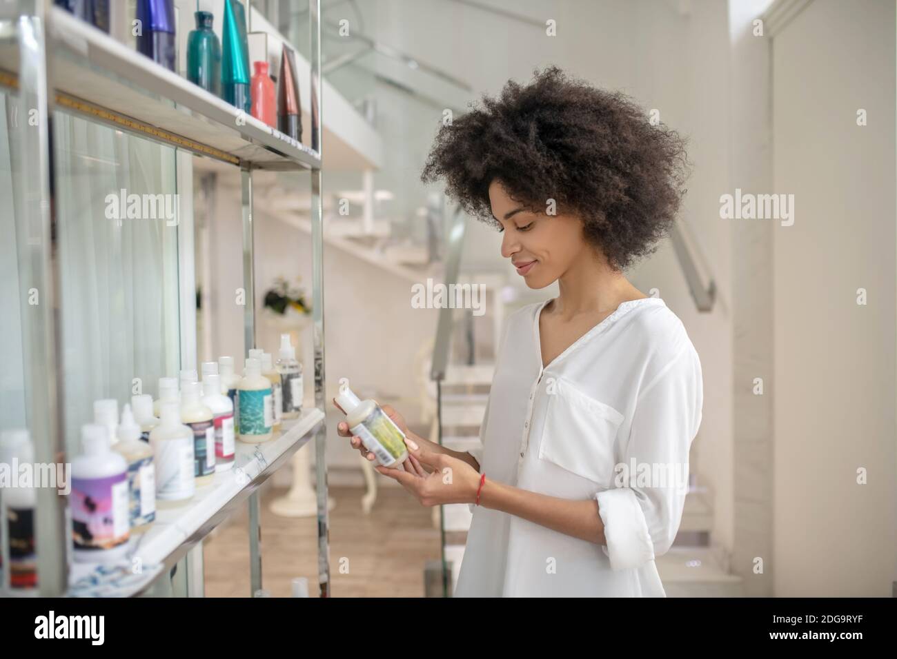 Young smiling girl interested in cosmetic product Stock Photo