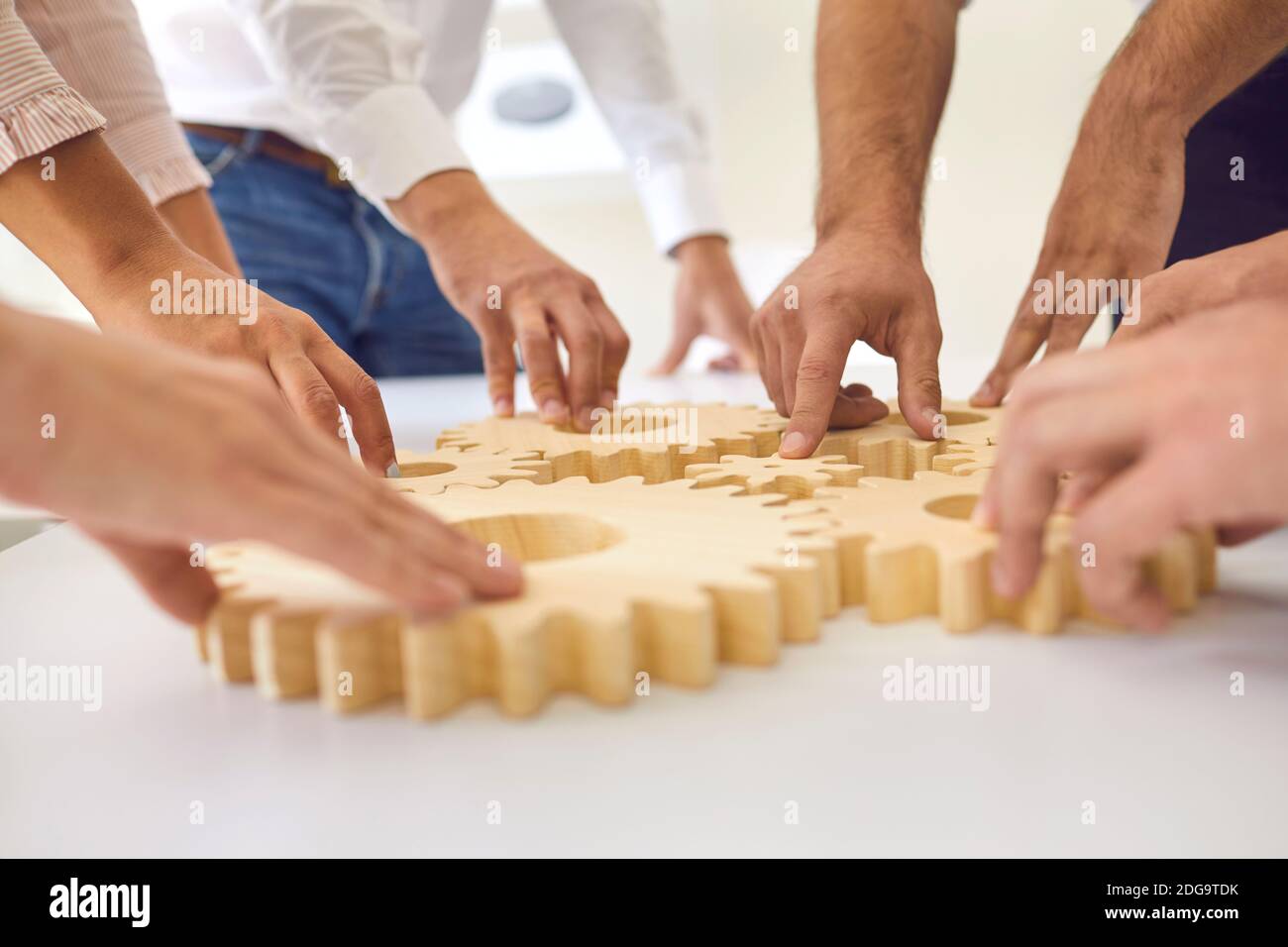 Hands of business people making whole picture of wooden gears on table together Stock Photo