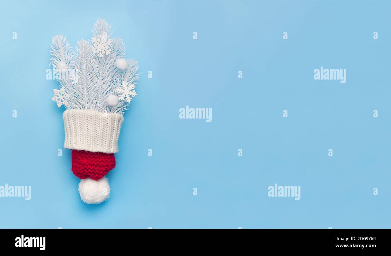 Christmas greeting card with red hat and white fir branches and snowflakes on blue backgroun. Xmas holiday postcard with place for your text. Happy Stock Photo