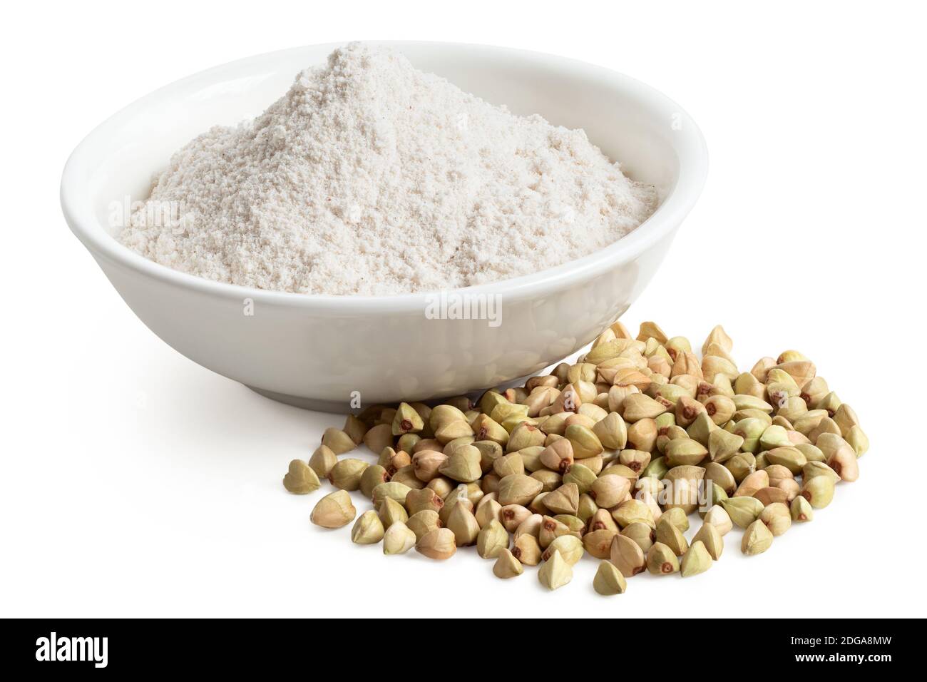 Buckwheat flour in a white ceramic bowl next to raw green buckwheat isolated on white. High angle. Stock Photo