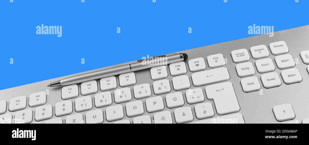 Keyboard and pen against blue background Stock Photo