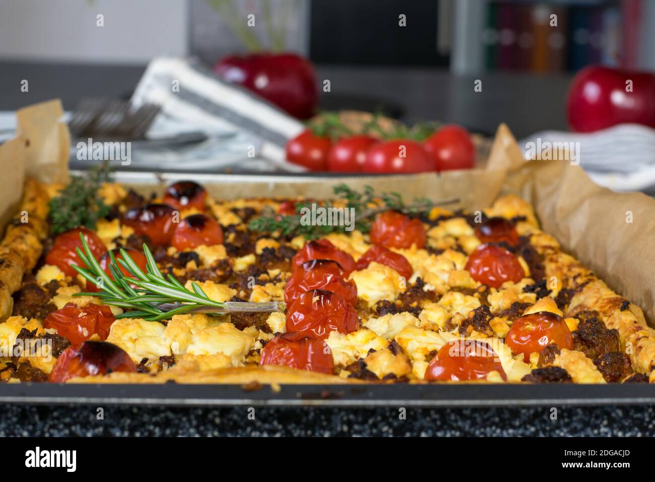 greek quiche baked with puff pastry and topped with minced meat, sheep cheese, tomatoes and herbs Stock Photo