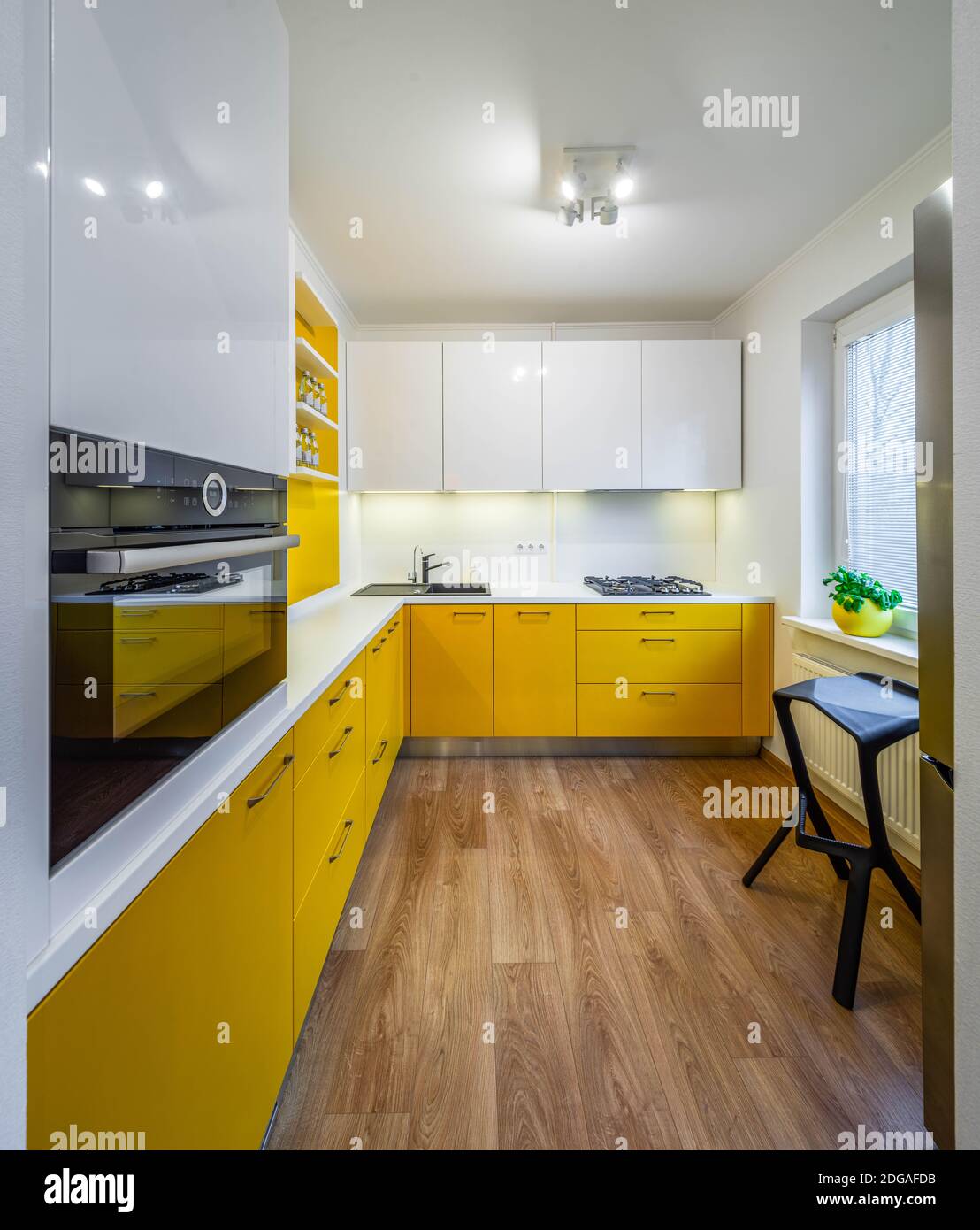 Contemporary interior of kitchen in modern flat. Yellow cabinets and  drawers. White counter. Gas stove, oven and sink Stock Photo - Alamy, image size:1108x1390