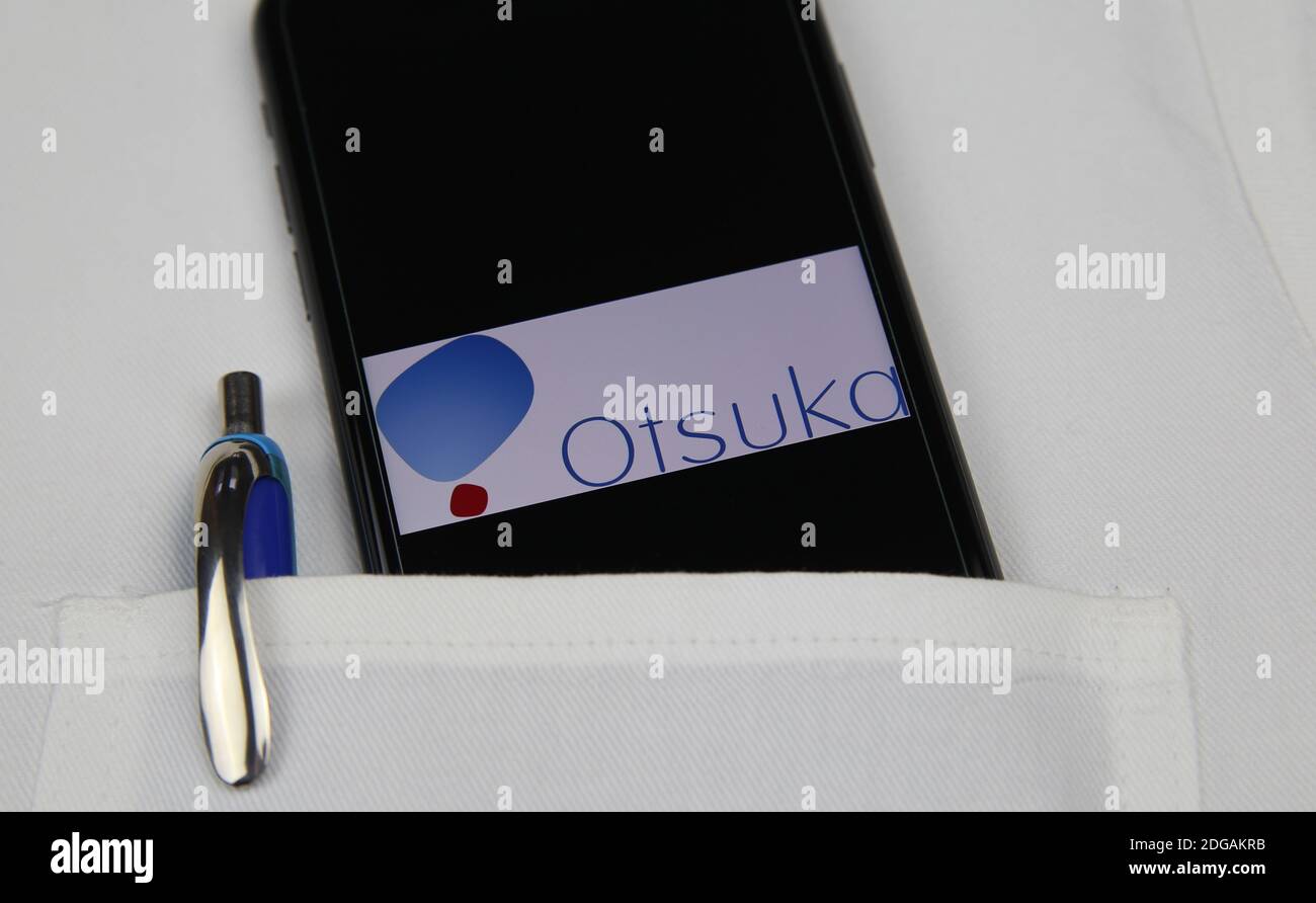 Viersen, Germany - April 9. 2020: Close up of mobile phone screen with logo lettering of Otsuka pharmaceutical company in pocket of white doctors coat Stock Photo