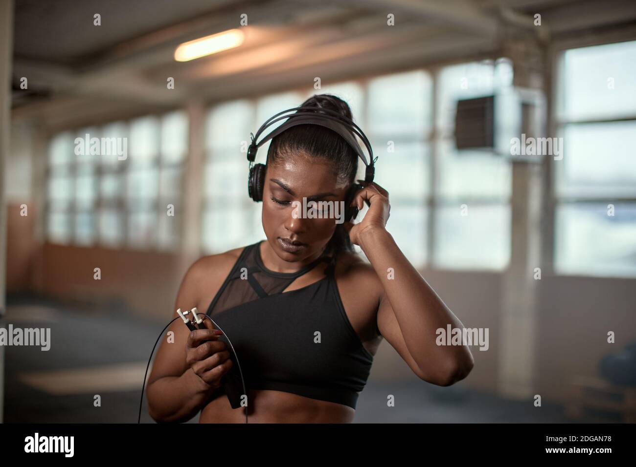 Strong ethnic female athlete adjusting headphones and listening to