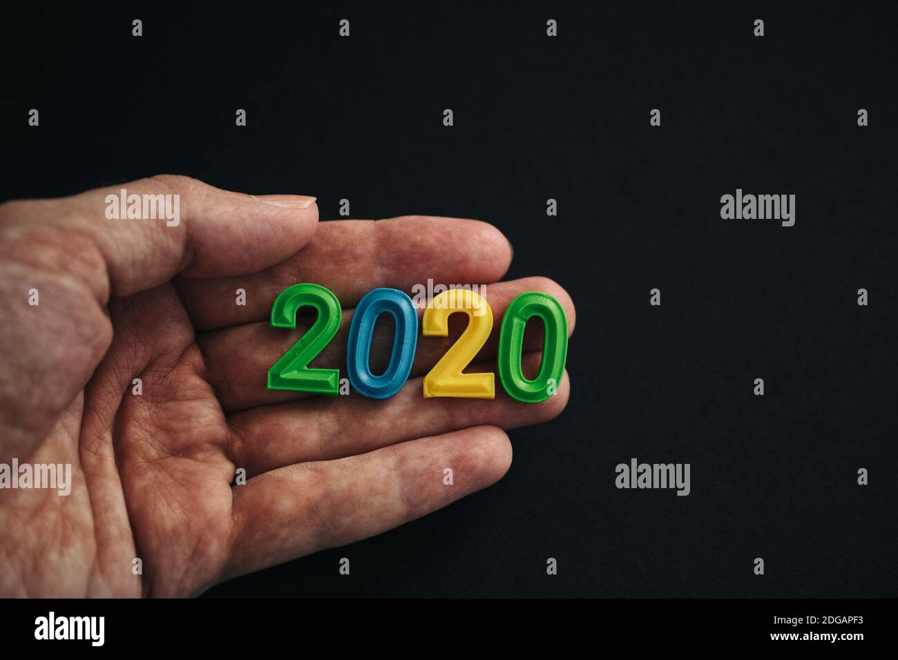 A man holding the year 2020 in his hand. Low key. Stock Photo