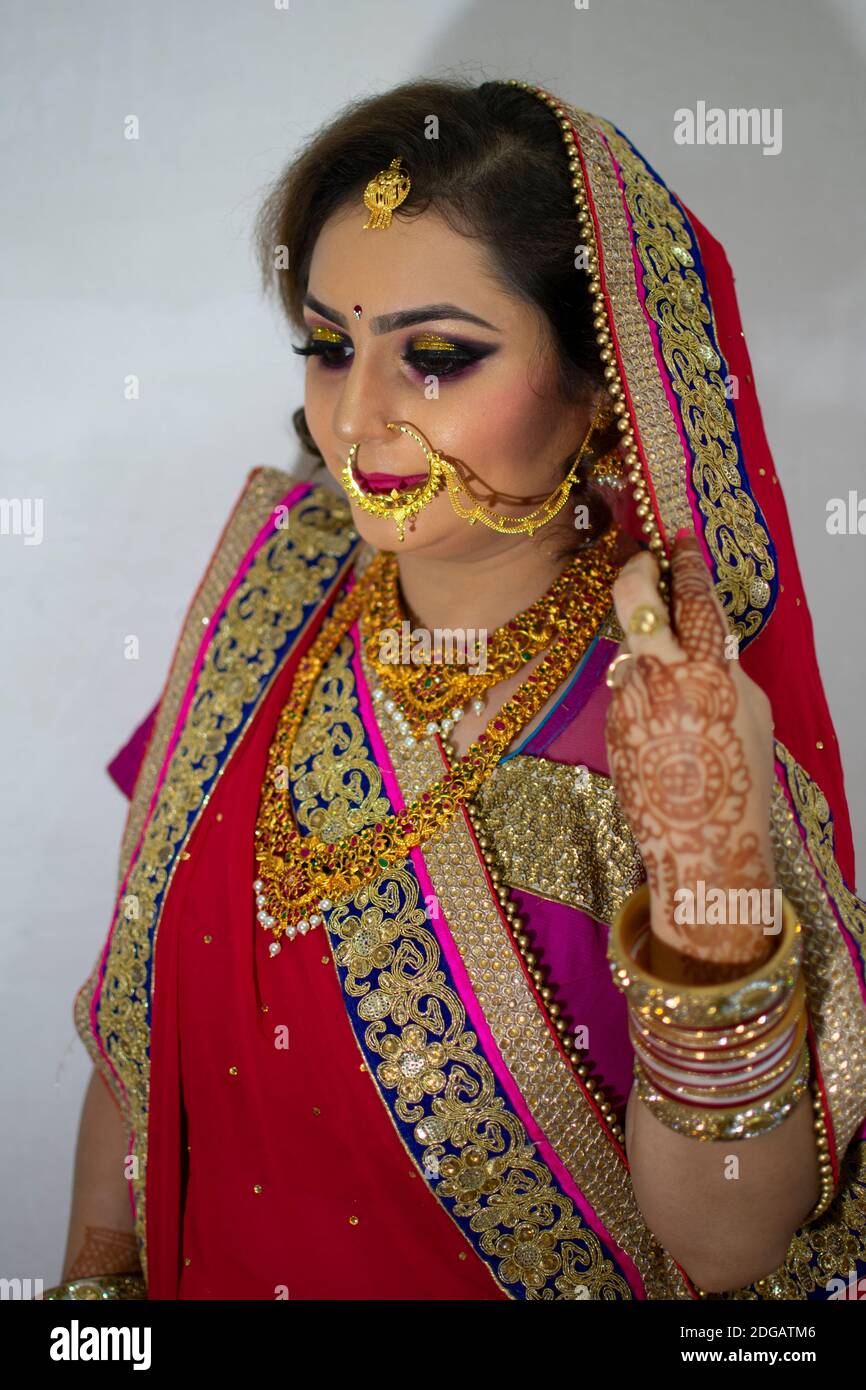 a beautiful Indian girl in bridal dress wearing red saree and gold