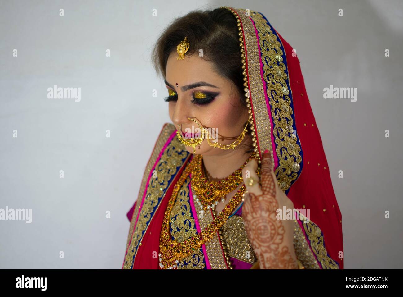 a beautiful Indian girl in bridal dress wearing red saree and gold ornaments Stock Photo