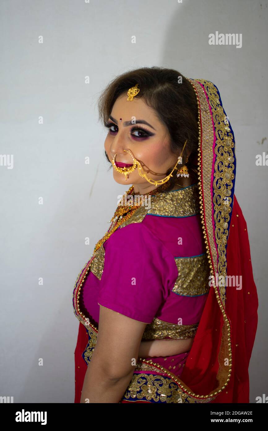 a beautiful Indian girl in bridal dress wearing red saree and gold ornaments Stock Photo
