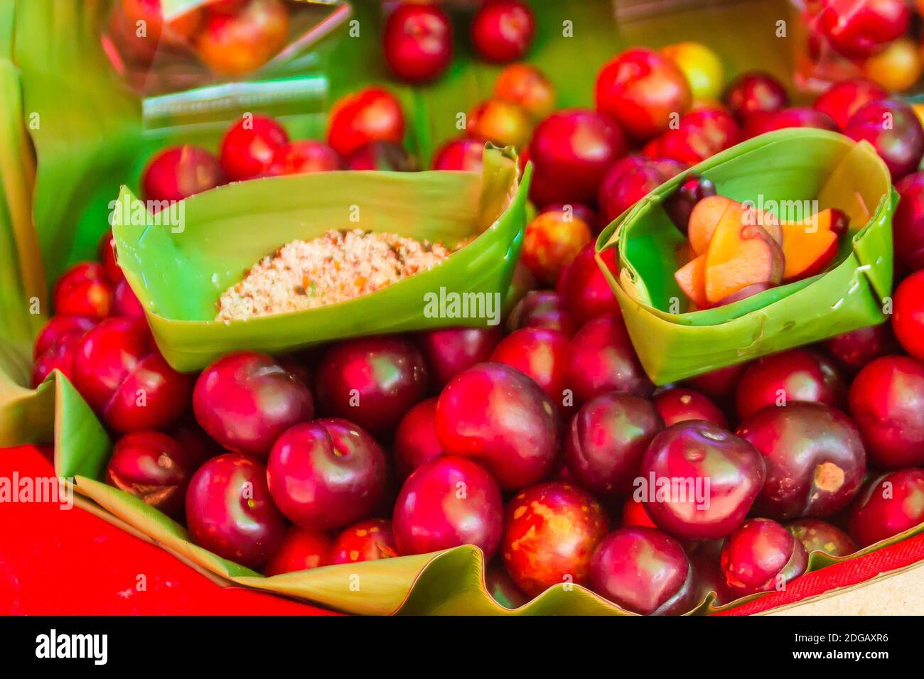 Red ramontchi fruits (Flacourtia indica) for sale at the local market in Chiang Rai, Thailand. Flacourtia indica also known as ramontchi, governor’s p Stock Photo