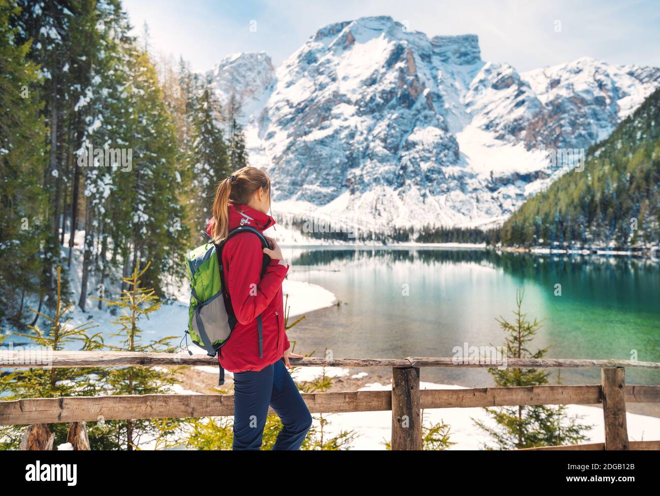 Young woman with backpack near wooden fence and Braies lake Stock Photo