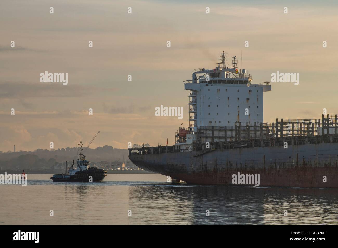 a tug boat towing a large big container ship in the port of southampton docks, uk Stock Photo