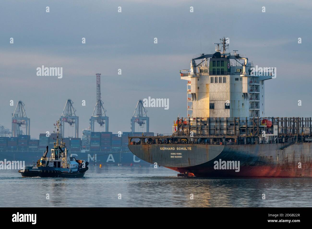 a large big container ship being towed by two tugs in the port of southampton docks, uk Stock Photo