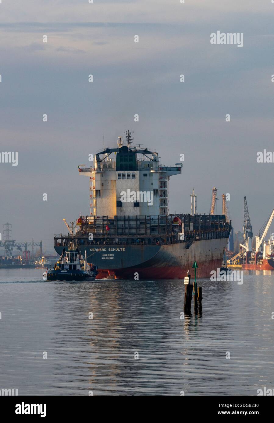 a large big container ship being towed by two tugs in the port of southampton docks, uk Stock Photo