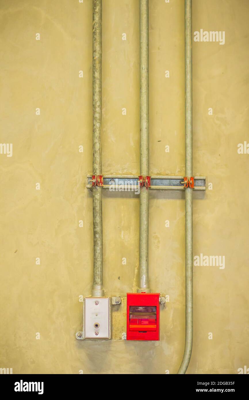 Red fire alarm pull box emergency and fire fighters telephone with conduit pipeline on concrete