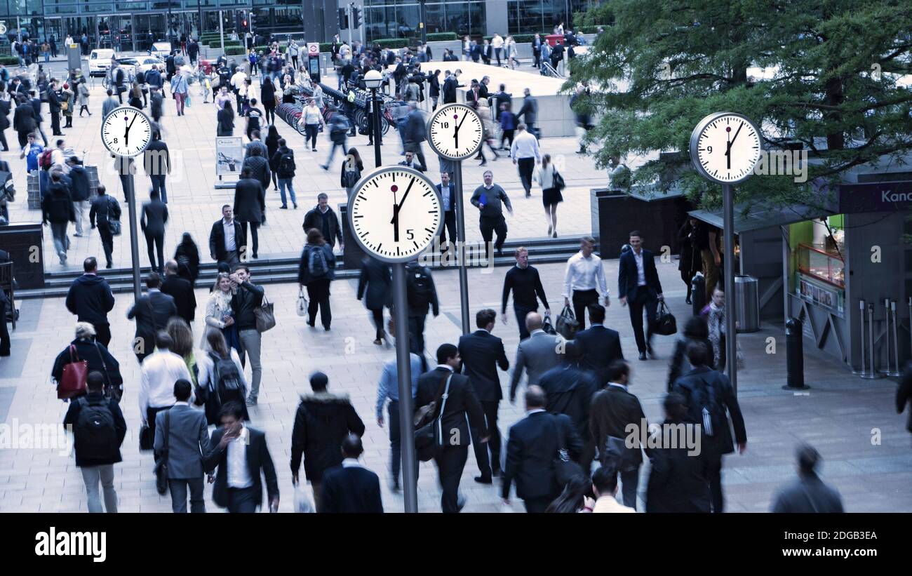 CLOCKS CANARY WHARF CROWDS COMMUTERS GOING HOME BUSY Canary Wharf Clocks 18.05 clock faces time London commuters office workers making daily commute home at end of working day South Colonnade Canary Wharf London UK Stock Photo