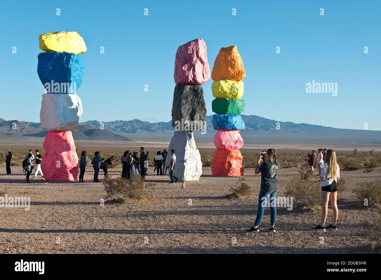 Two girls photograph Seven Magic Mountains, an artwork of limestone