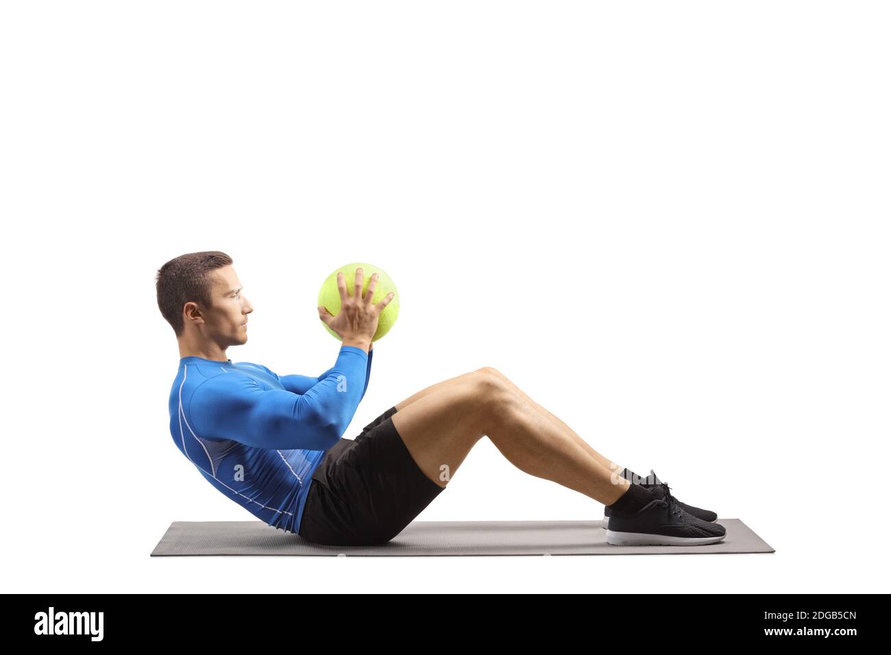Young man in sportswear exercising with a ball on the floor on an exercise mat isolated on white background Stock Photo