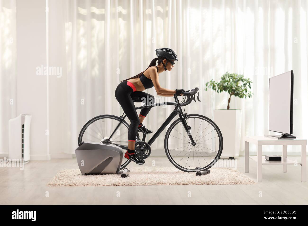 Young woman spinning a bicycle at home fixed on a trainer Stock Photo