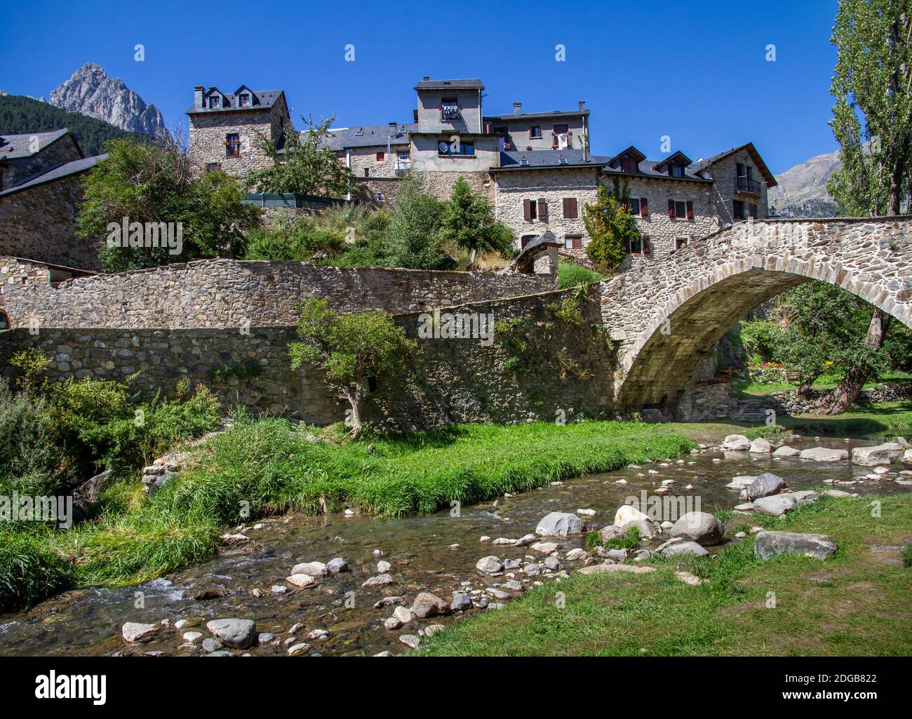mountain village built in stone with a bridge over which a river flows on a sunny summer day, Sallent de Gallego, Huesca, Pyrenees Spain, horizontal Stock Photo
