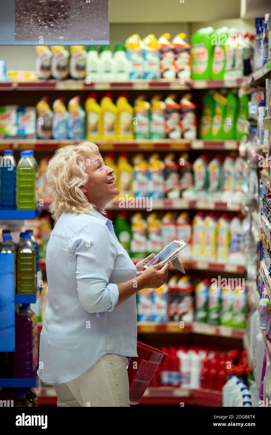 A smiling middle aged woman in a household section of a supermarket Stock Photo