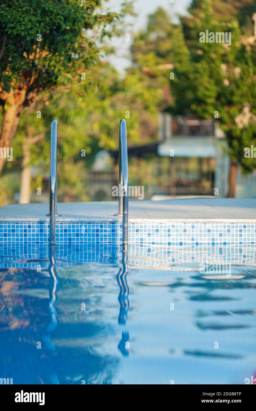 An open swimming pool with a shiny railing and a sunny background Stock Photo