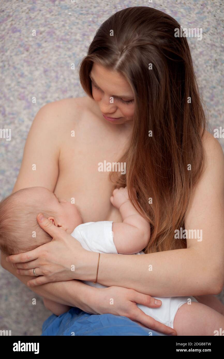 A long haired young woman breastfeeding a baby Stock Photo