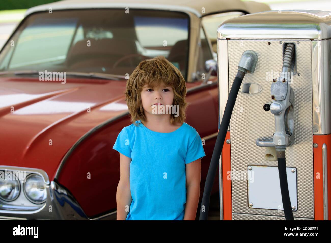 Kid boy at the gas station. Waiting for fuel. Kid fueling retro car at