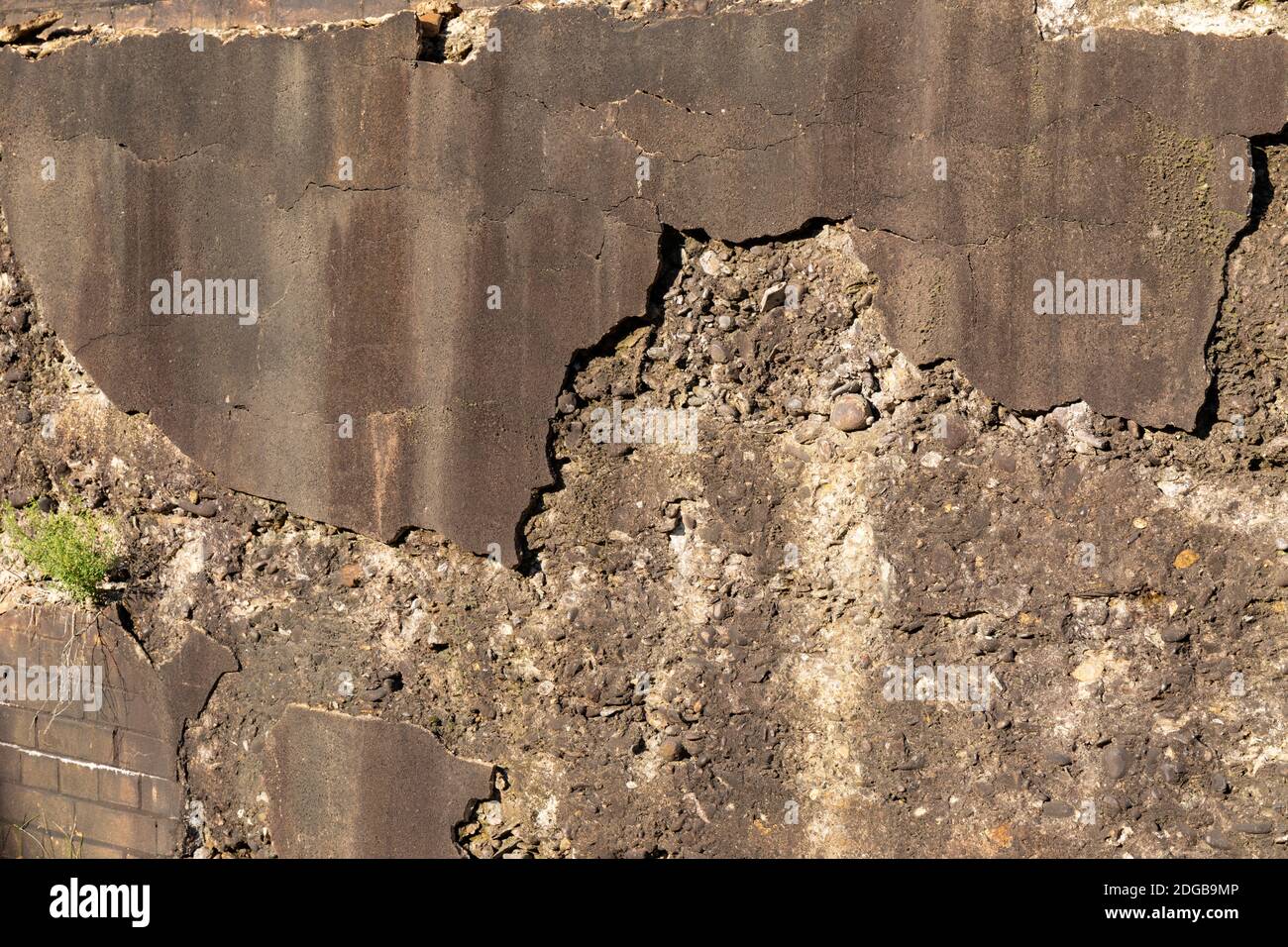 Weathered wall of heavy concrete aggregate, crumbling stucco skim coat, dirty brown patina, creative industrial copy space, horizontal aspect Stock Photo