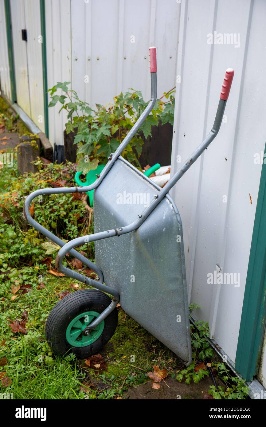 Aluminium wheelbarrow against garden shed Stock Photo