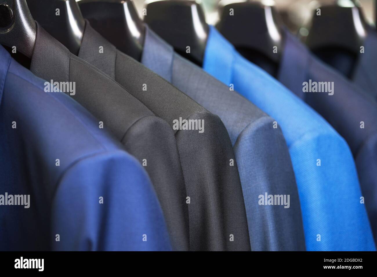 Close up luxurious style gentlemen suit row, hanging in a closet. Stock Photo