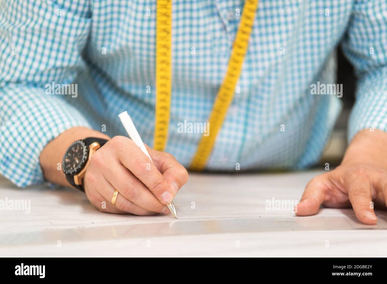Tailor hands mark drawing on craft paper for making patterns. Stock Photo