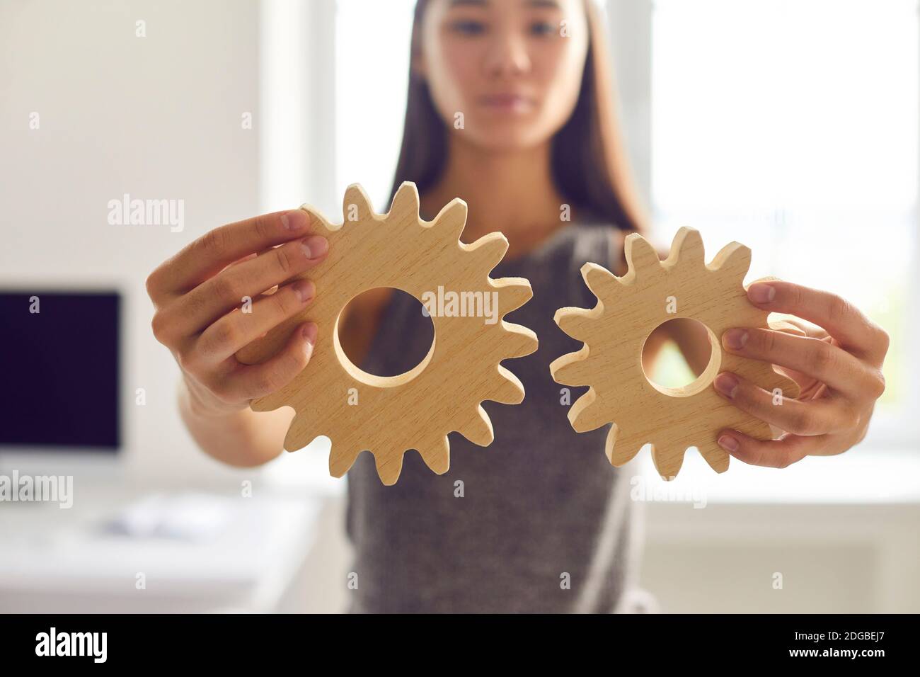 Woman joining cogwheels as metaphor for finding business solutions, integration and cooperation Stock Photo