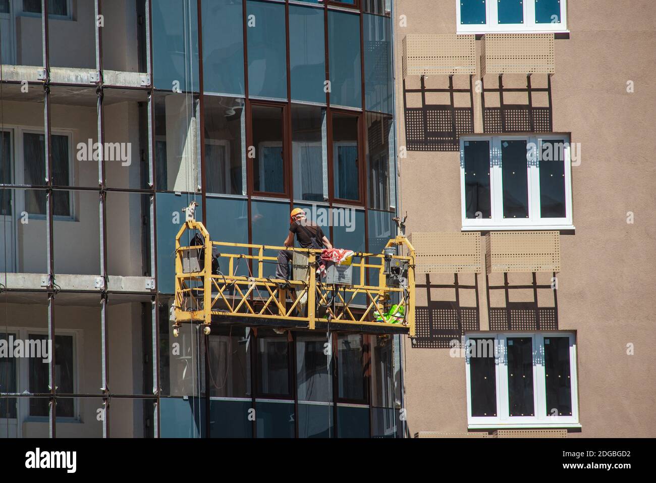 Window workers on a suspended platform working on a bilding facade Stock Photo