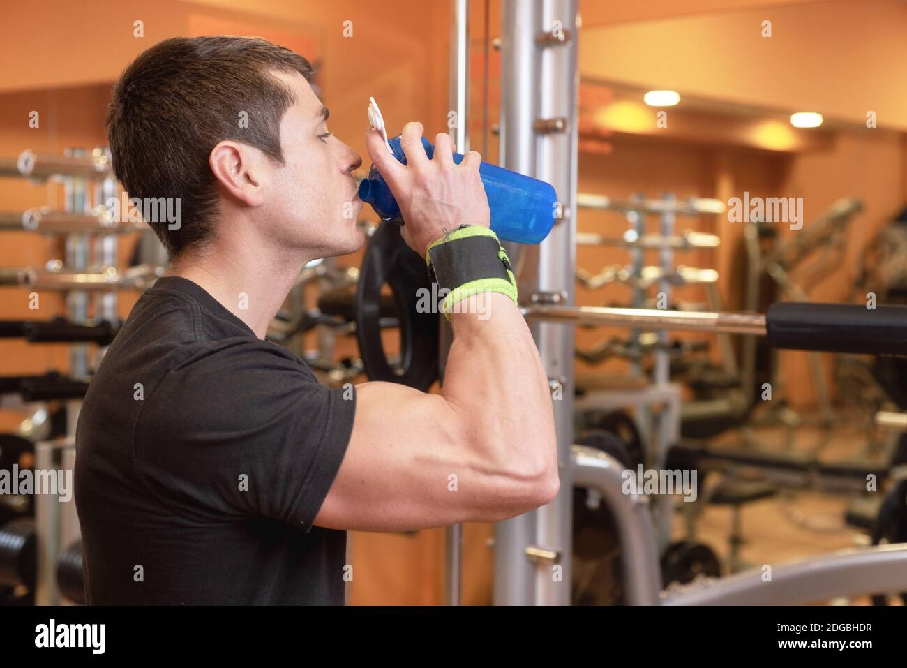 Muscular man drink water from blue bottle in the gym Stock Photo - Alamy