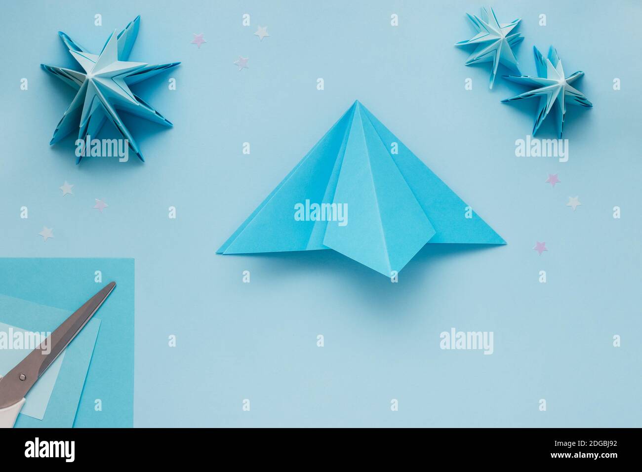 Simple origami 3D Christmas tree made from blue paper. Step by step instruction, step 9. Open the right part and flatten it Stock Photo
