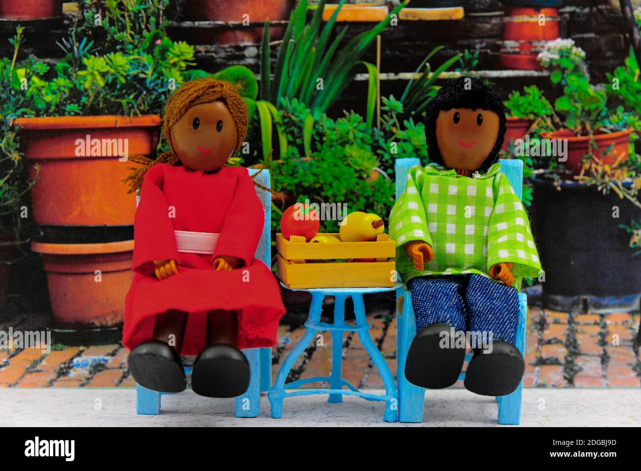 Young Couple sitting in Garden.  Garden Furniture and Wooden figurines / dolls. Stock Photo