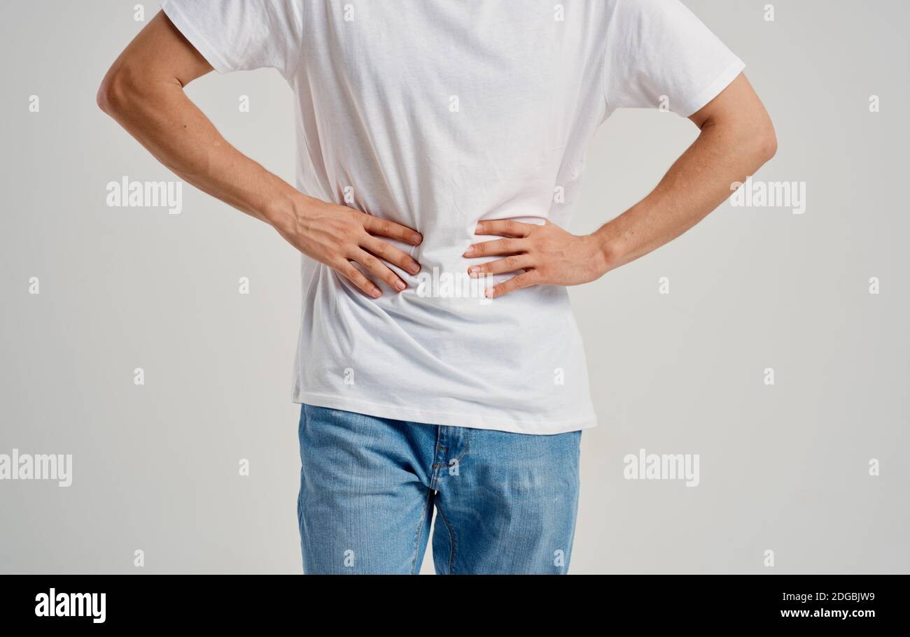 man in white tshirt and jeans touching his stomach with his hands