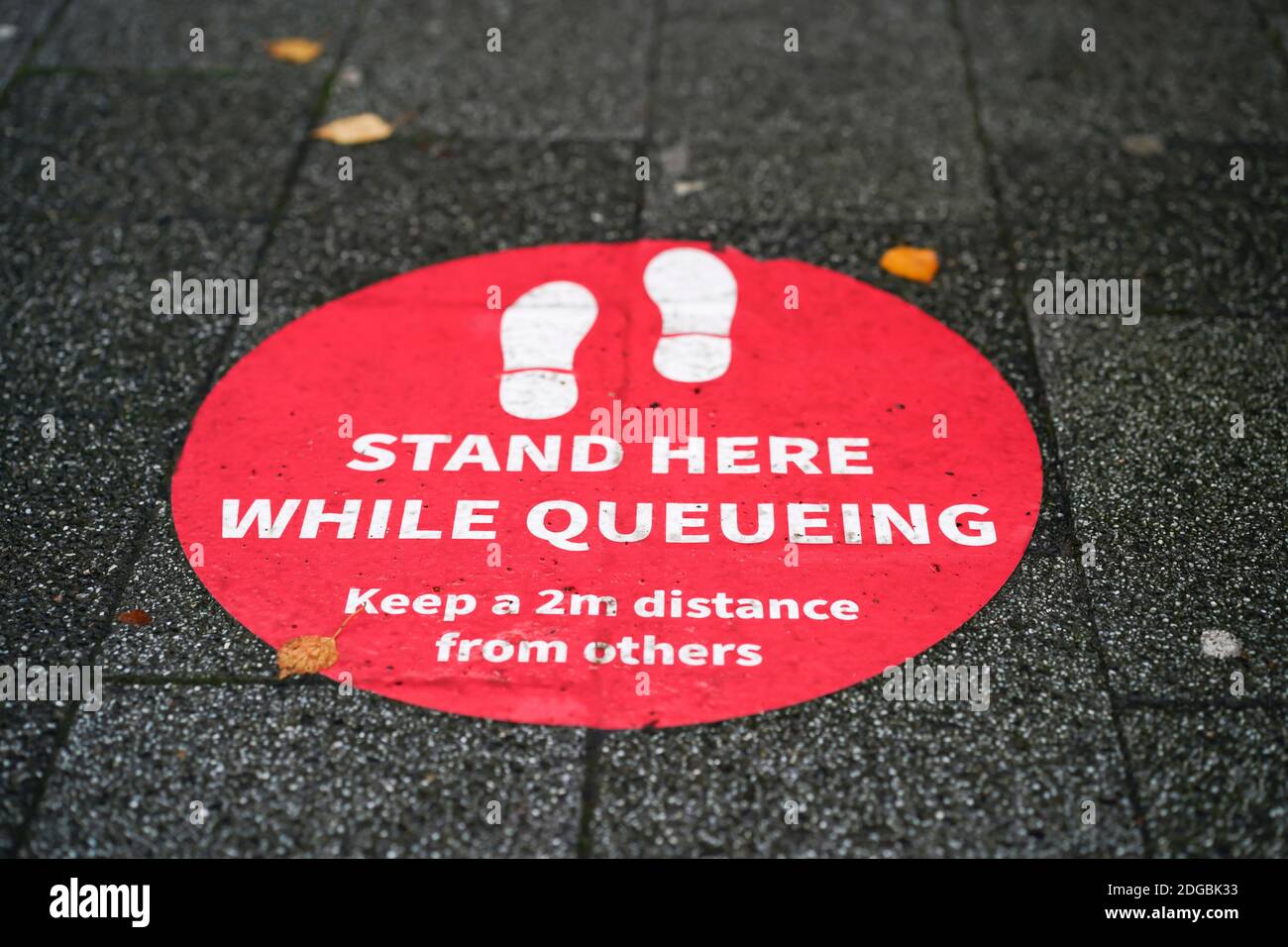 Social distance floor sign marker in UK town centre. Public advice to keep 2m distance from others when queueing during coronavirus pandemic. Stock Photo