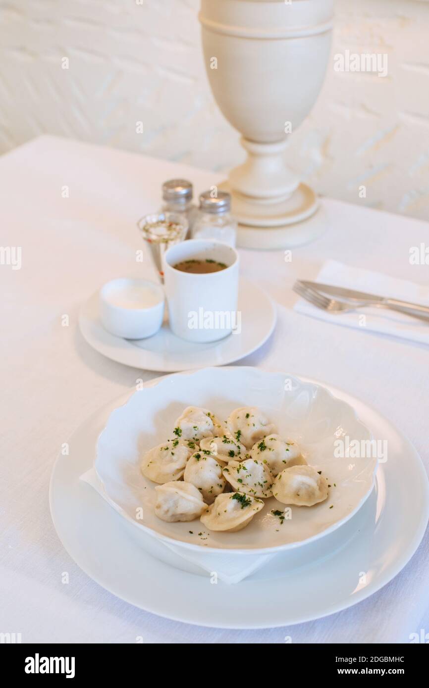 Bowl of Russian pelmeni dumplings on a table in a restaurant Stock Photo