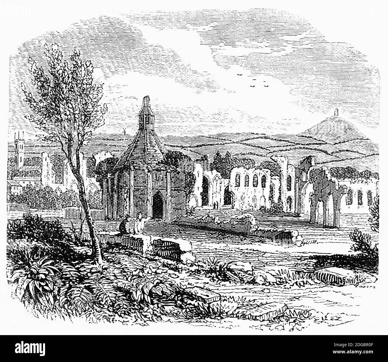 A 19th century view of the Abbot's Kitchen in Glastonbury Abbey, Somerset, England, with the Tor in the background. The monastery, founded in the 7th century was by the 14th century one of the richest and most powerful monasteries in England until suppressed during the Dissolution of the Monasteries under King Henry VIII of England. From the 12th century the Glastonbury area has been associated with the legend of King Arthur, a connection promoted by medieval monks who asserted that Glastonbury was Avalon. Christian legends have also claimed that the abbey was founded by Joseph of Arimathea in Stock Photo