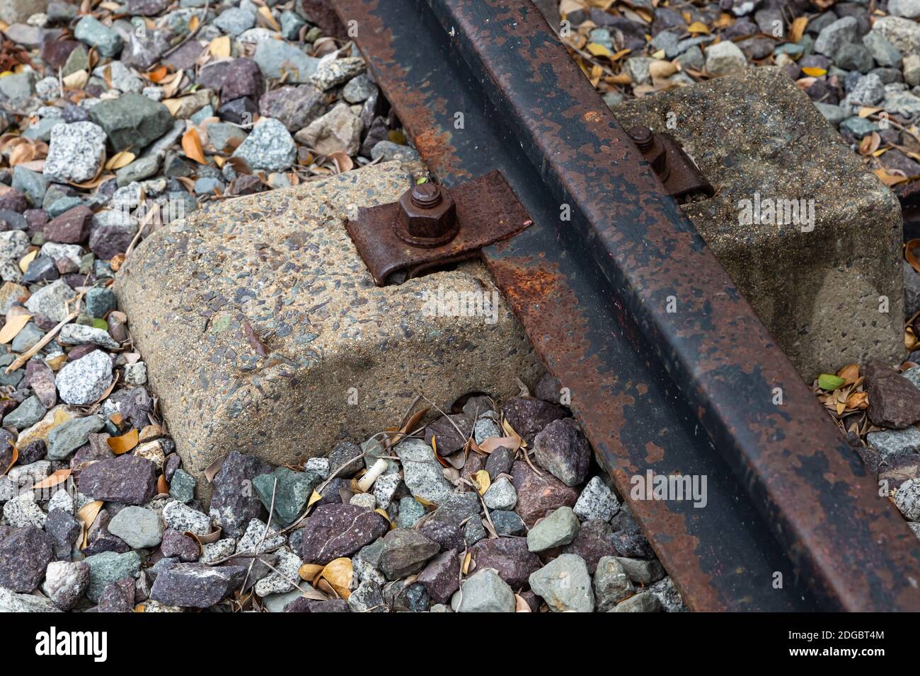 Railway track of iron rails old rusty and cement sleeper against a gravel background Stock Photo