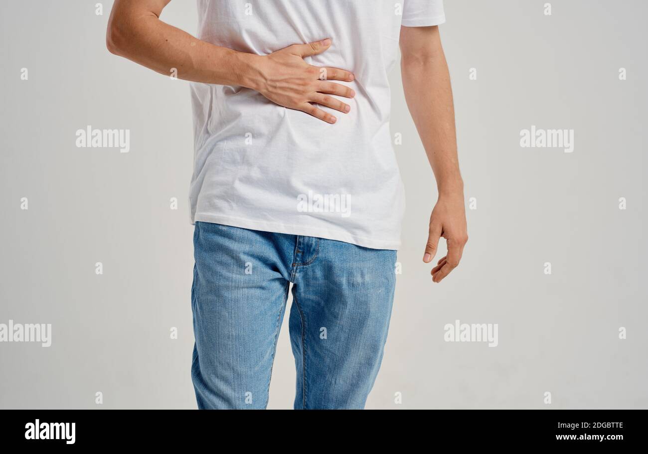man in white tshirt and jeans touching his stomach with his hands